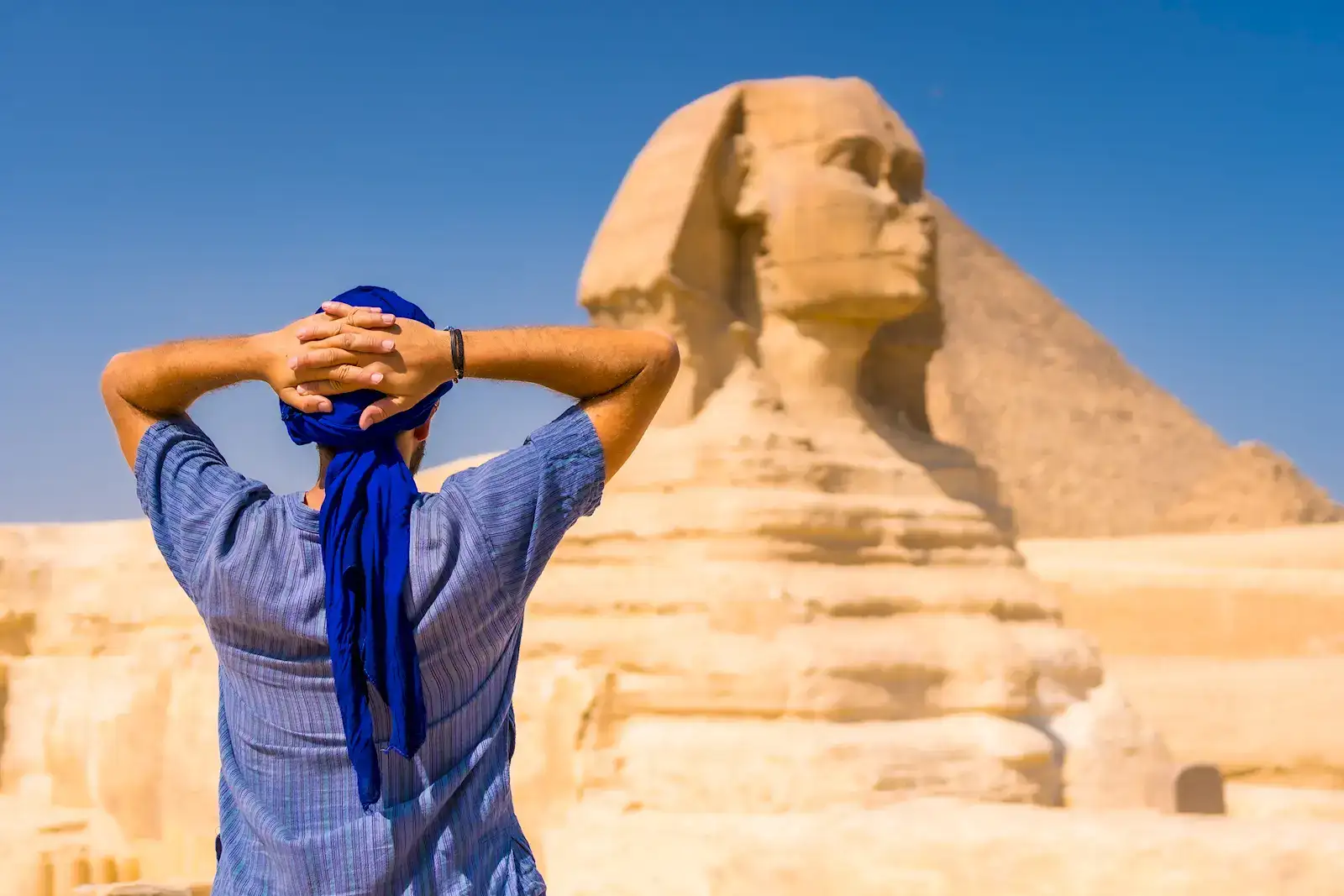 A traveller in a blue headscarf looking up at the Great Sphinx of Giza, Egypt