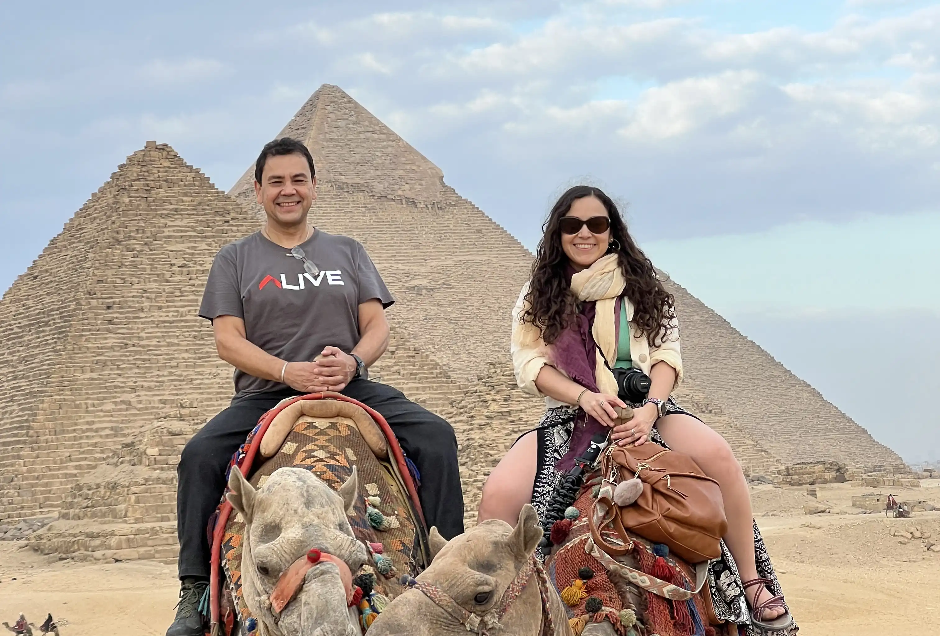 Two travellers on camels in front of the Giza pyramids near Cairo, Egypt